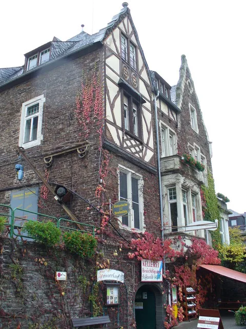 Historische Senfmühle Cochem: Bruchstein- und Fachwerkhaus mit rot gefärbtem Wilden Wein und Schildern über dem Eingang