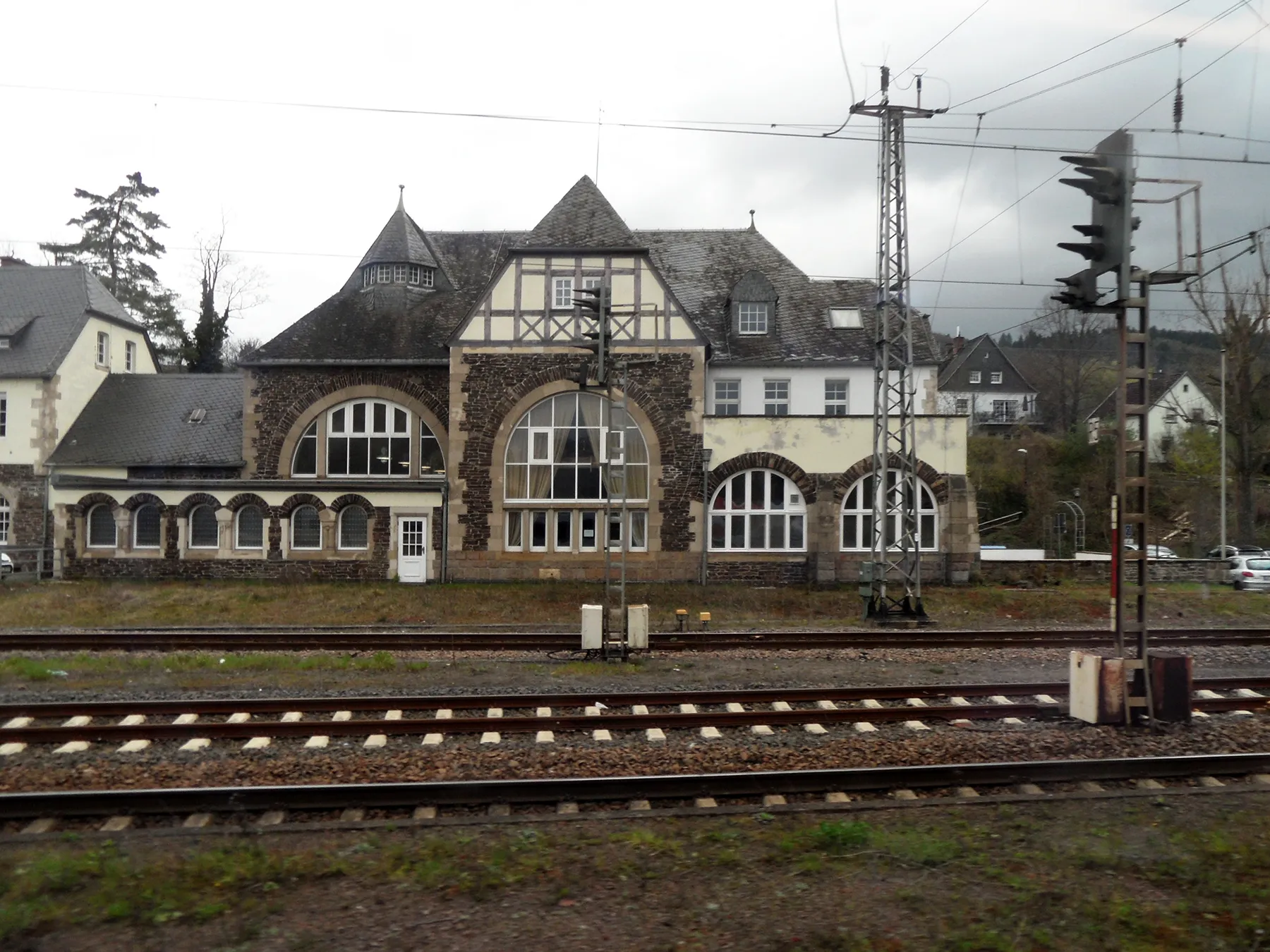 Empfangsgebäude des Bahnhofs Bullay an der Mosel, davor mehrere Gleise, ein Signal und Oberleitungsmasten