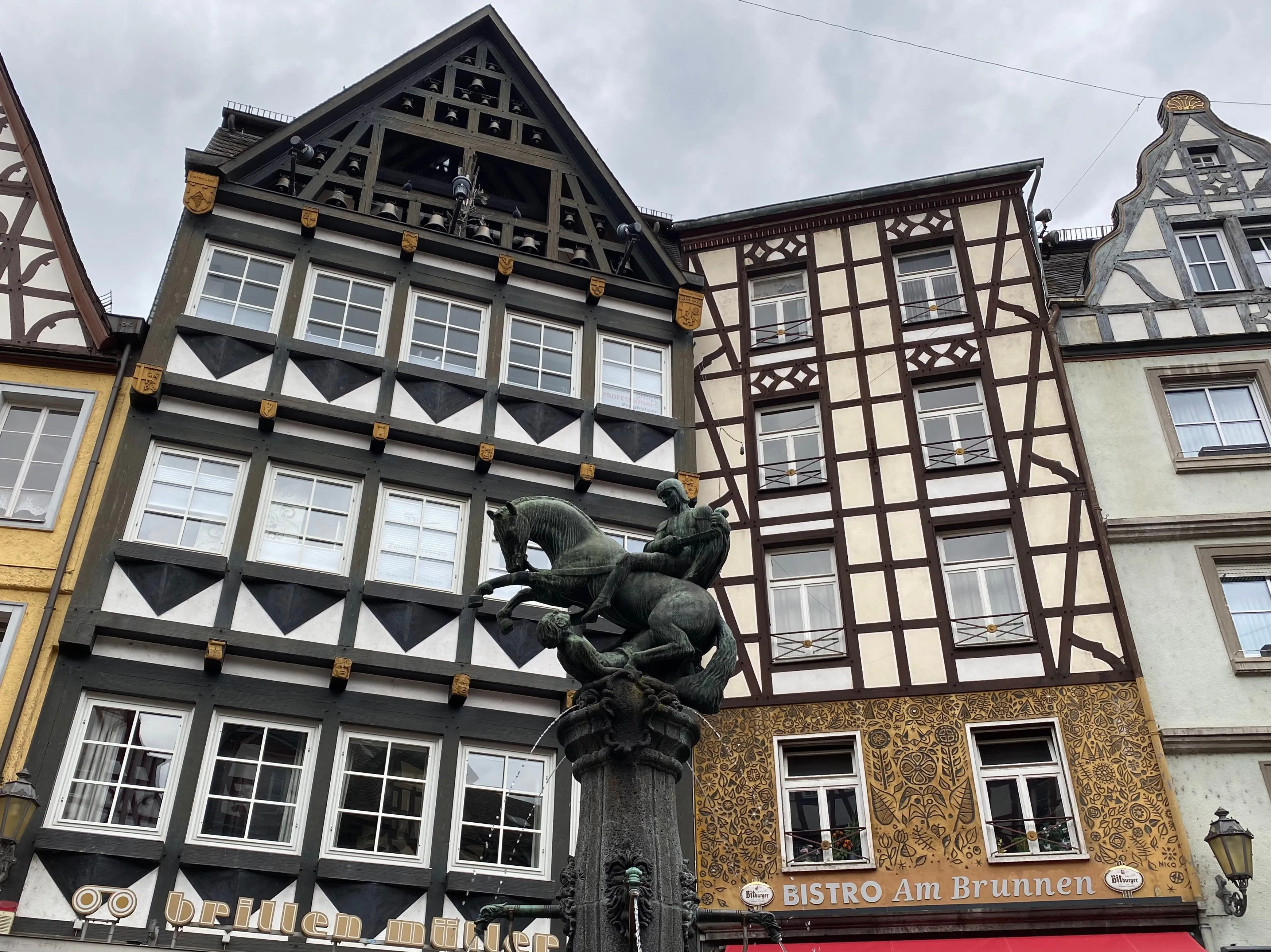Fachwerkhäuser am Cochemer Marktplatz mit Ladenschildern, davor der Brunnen mit der Reiterfigur