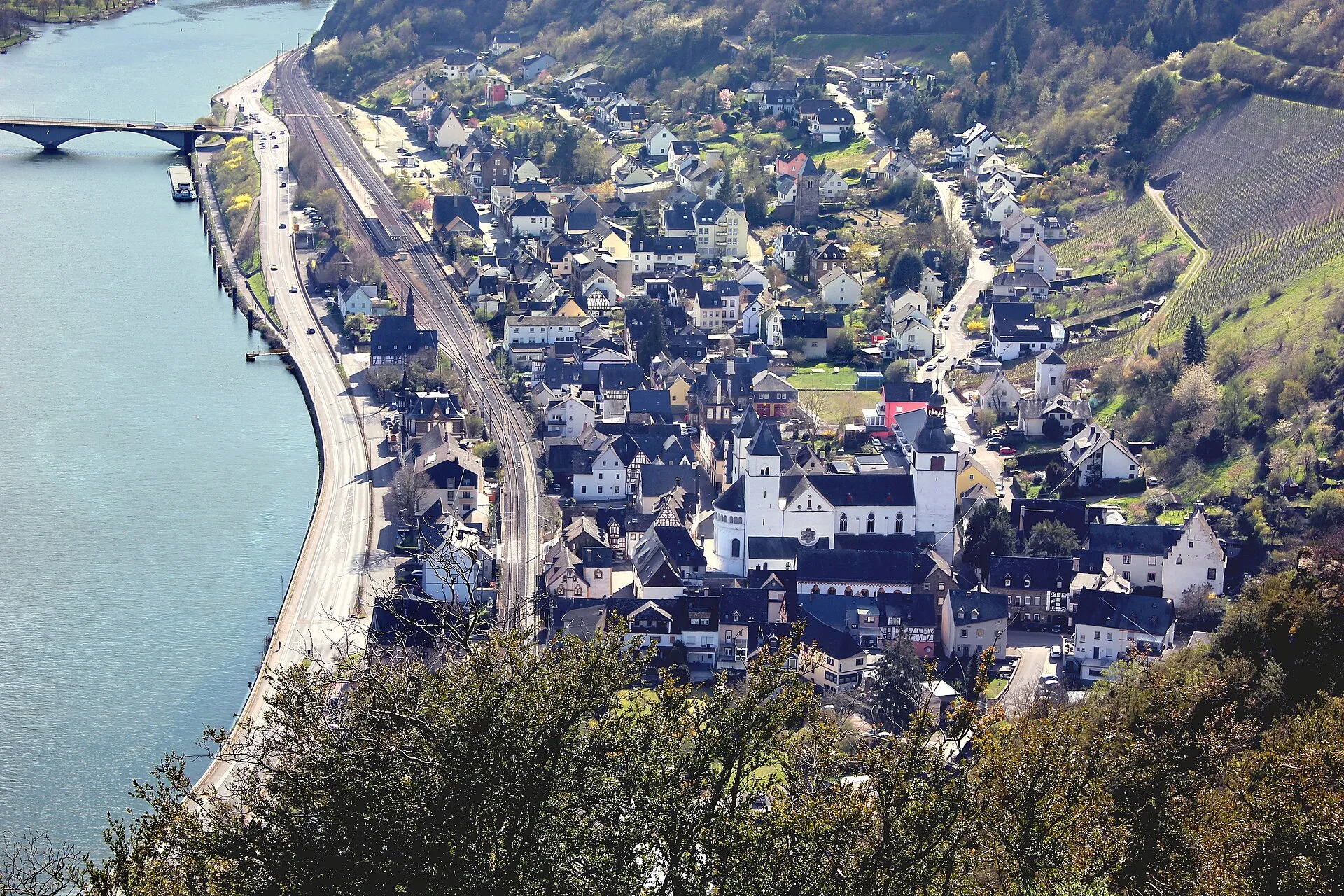 Blick von oben auf Karden an der Mosel: Stiftskirche St. Castor, Bahnlinie und Uferstraße am Fluss