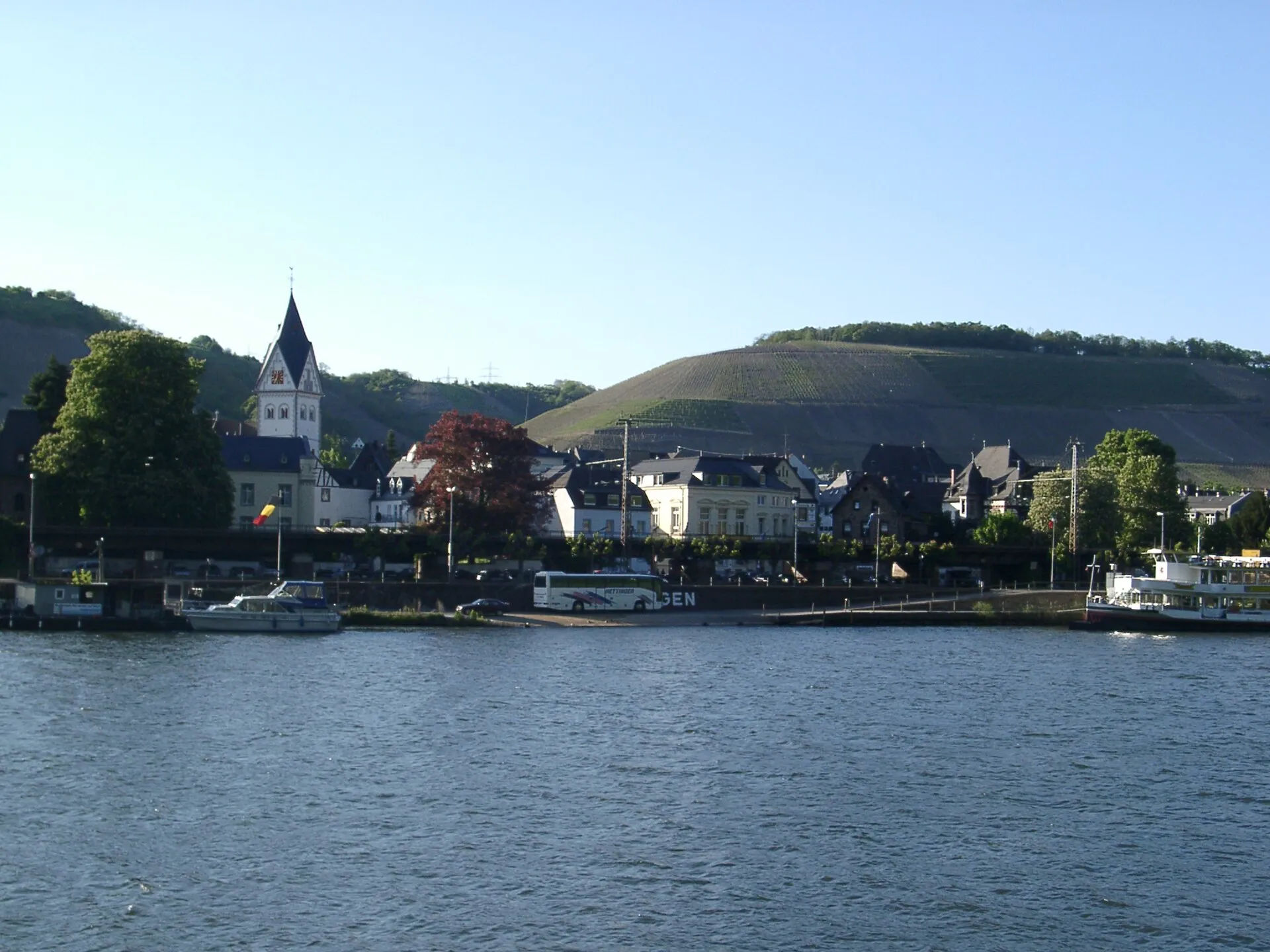Winningen vom gegenüberliegenden Moselufer aus gesehen, mit Kirchturm, Uferzeile und dem Weinberghang dahinter