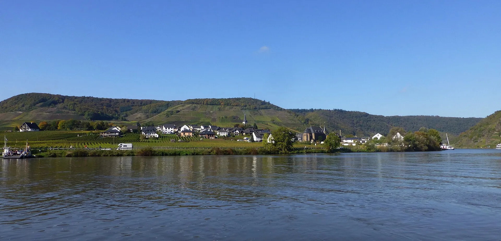 Blick über die Mosel auf Ellenz-Poltersdorf, dessen Weinberge bis an die Häuser des Orts heranreichen
