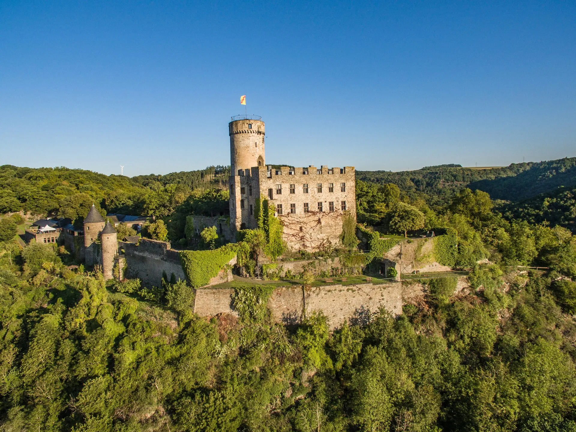 Burg Pyrmont über dem bewaldeten Tal des Elzbachs, Luftaufnahme im Sommer