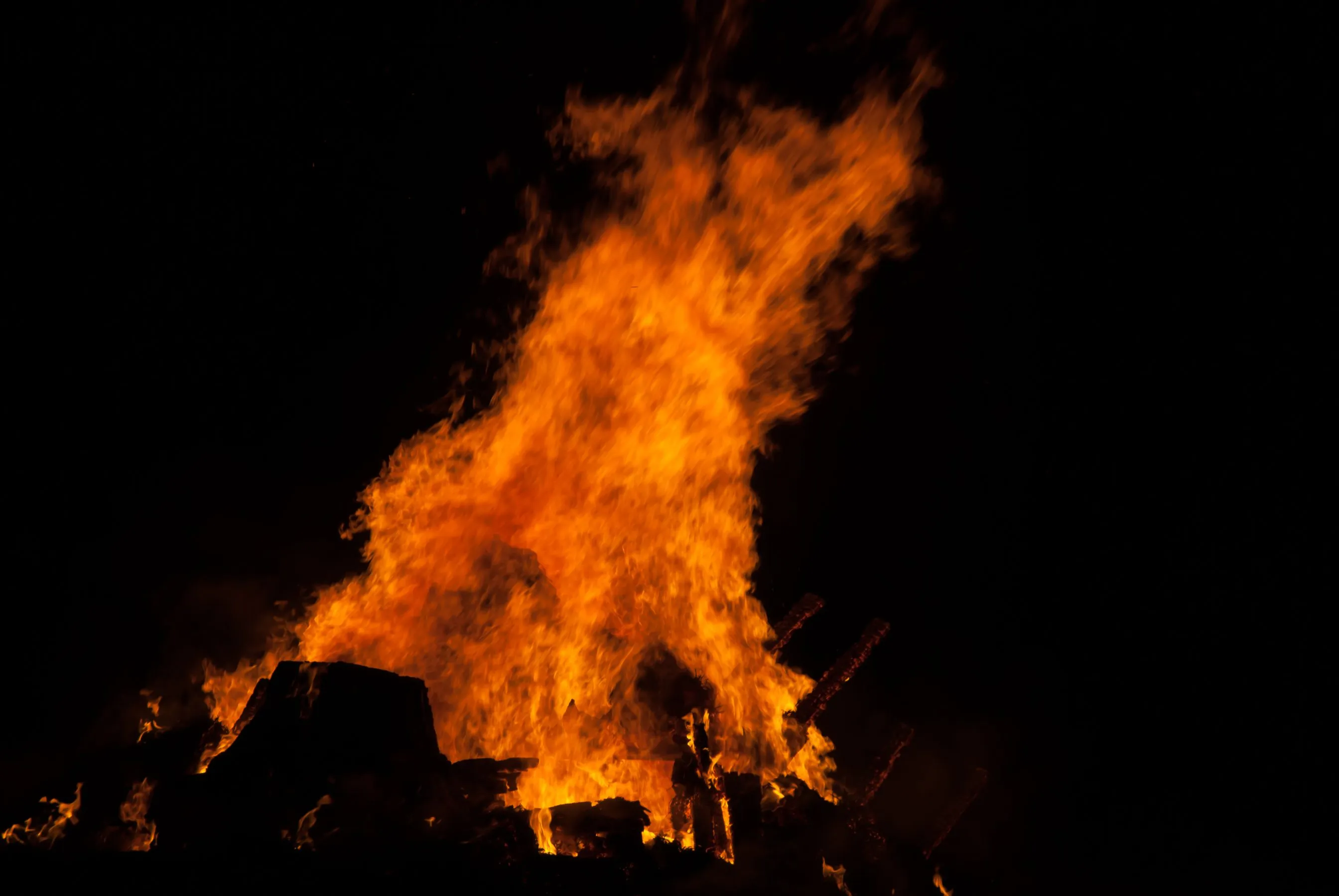 Loderndes Martinsfeuer aus Holzscheiten und Reisig vor schwarzem Nachthimmel